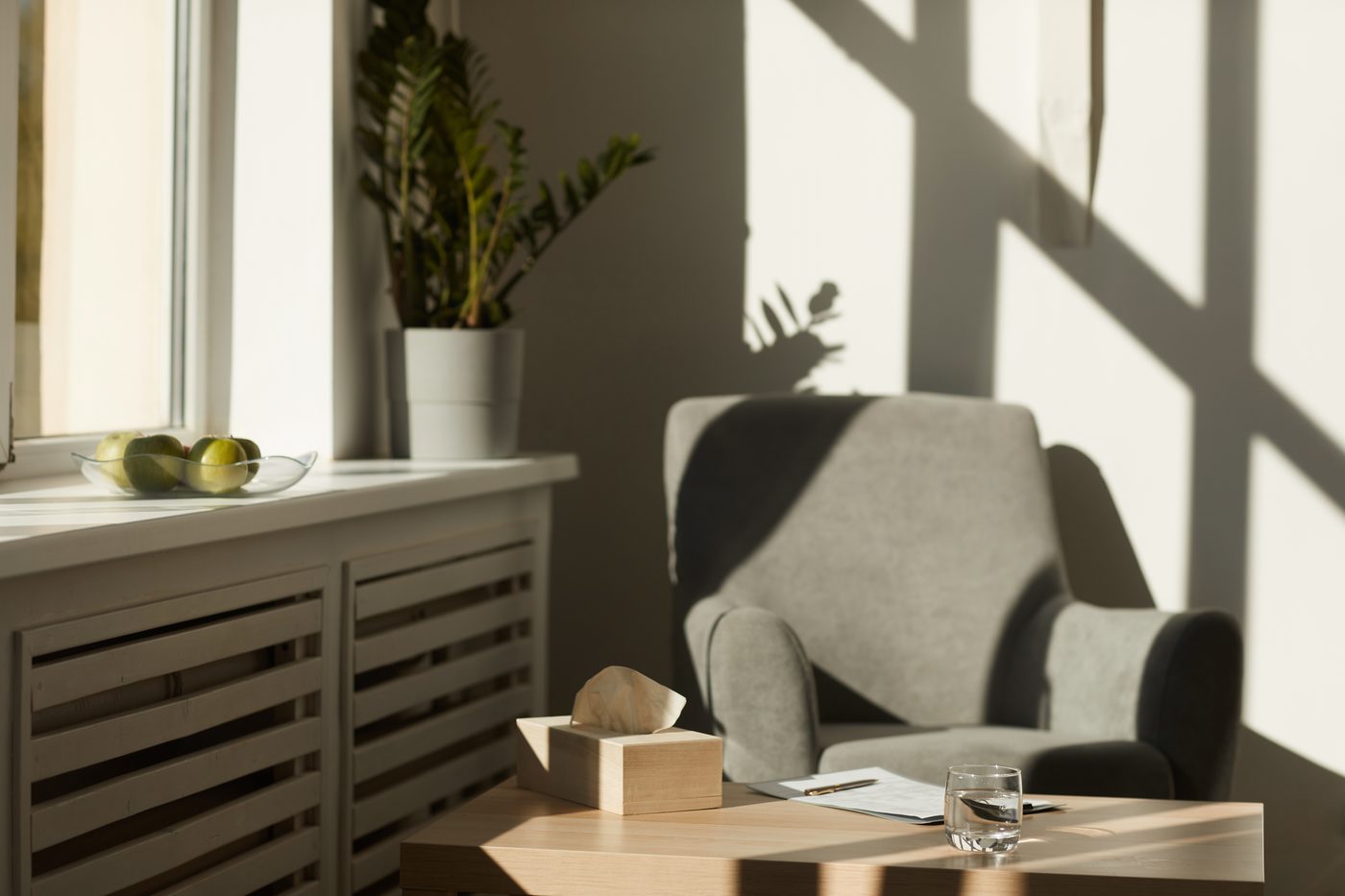 A quiet room with an armchair, a pot plant and soft daylight through the window